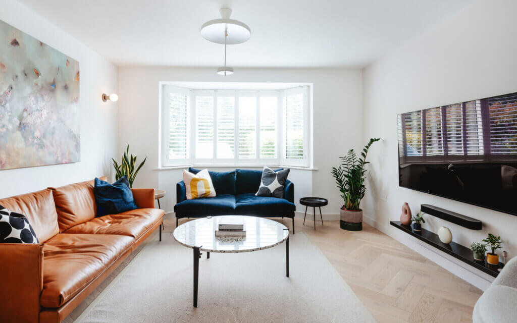 paperback herringbone, create collection, living room with orange and blue sofas and white rug.