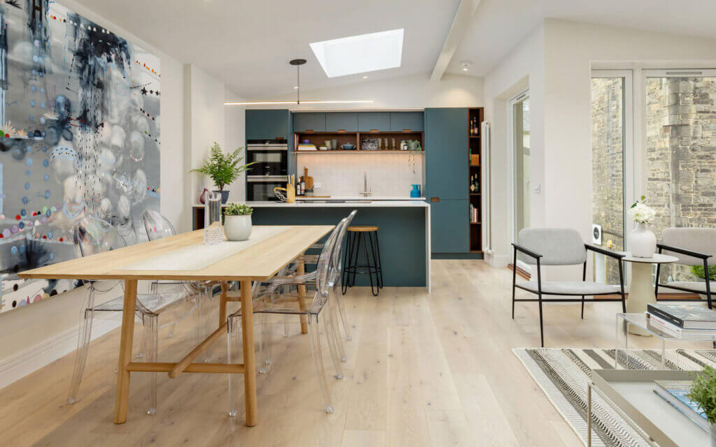petworth plank, project collection. Plank wood floors in an open plan kitchen with blue cabinets and a wooden table with clear acrylic chairs.